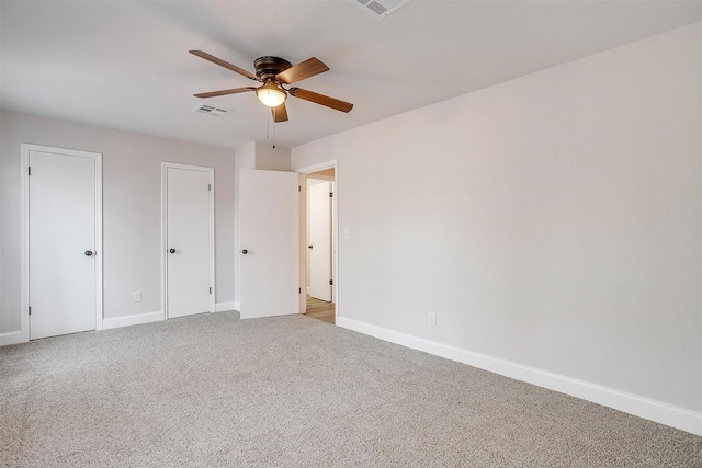 unfurnished bedroom with two closets, light colored carpet, and ceiling fan