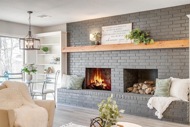 interior space with a brick fireplace, a textured ceiling, and light wood-type flooring