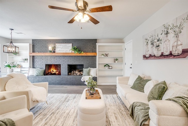 living room featuring ceiling fan, a fireplace, and light hardwood / wood-style flooring