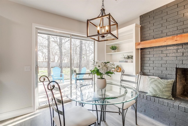 dining space featuring an inviting chandelier, built in features, a fireplace, and light hardwood / wood-style floors