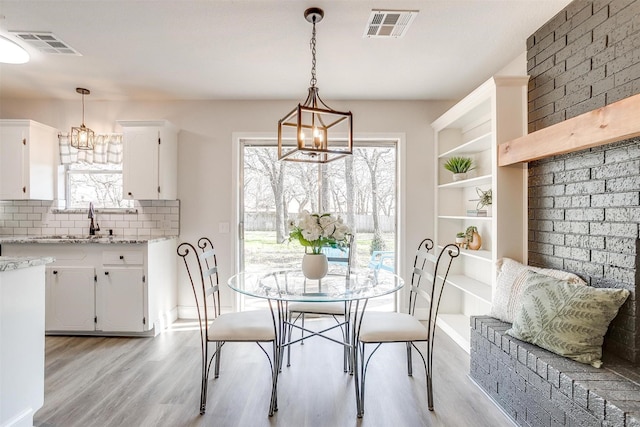 dining area featuring sink, a chandelier, and light hardwood / wood-style floors