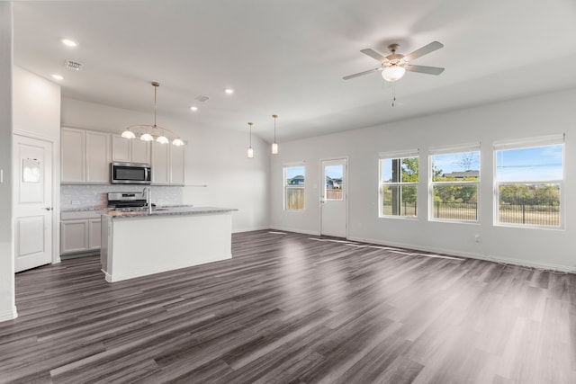 kitchen featuring a center island with sink, hanging light fixtures, stainless steel appliances, light stone countertops, and white cabinets