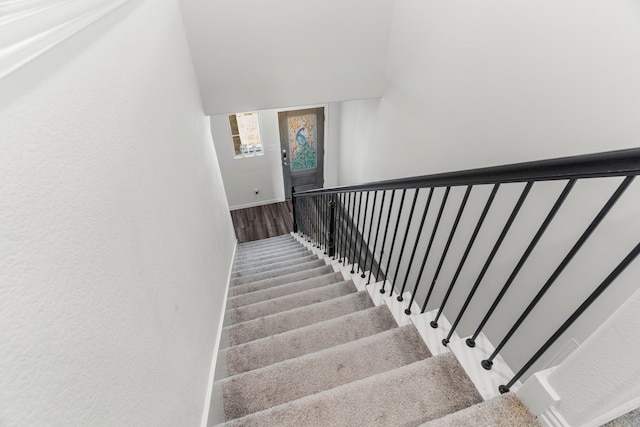 staircase with vaulted ceiling and carpet