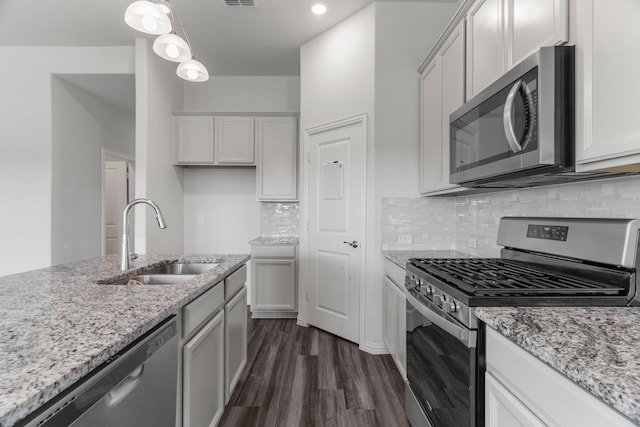 kitchen featuring pendant lighting, stainless steel appliances, light stone countertops, and sink