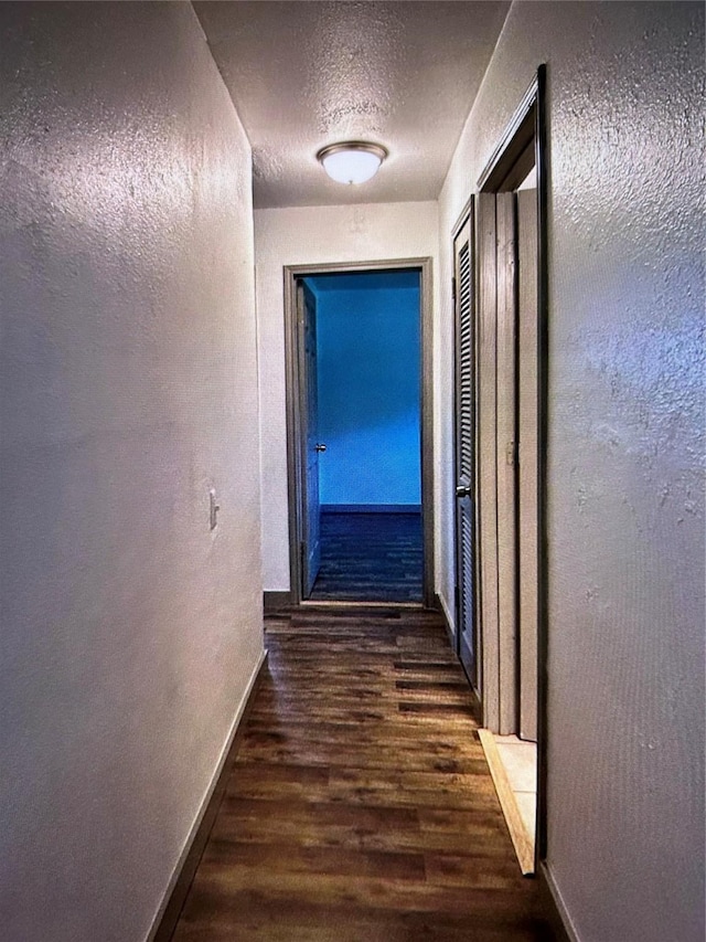 hall with dark wood-type flooring and a textured ceiling