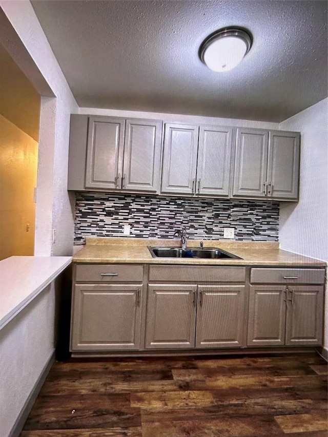 kitchen featuring sink, a textured ceiling, backsplash, and dark hardwood / wood-style flooring