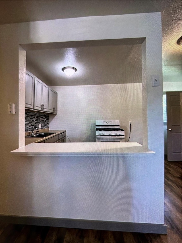 kitchen featuring tasteful backsplash, dark hardwood / wood-style floors, white range with gas cooktop, and sink