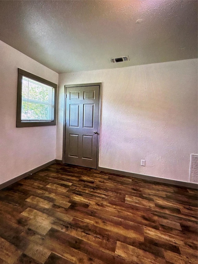 unfurnished bedroom with dark hardwood / wood-style flooring and a textured ceiling