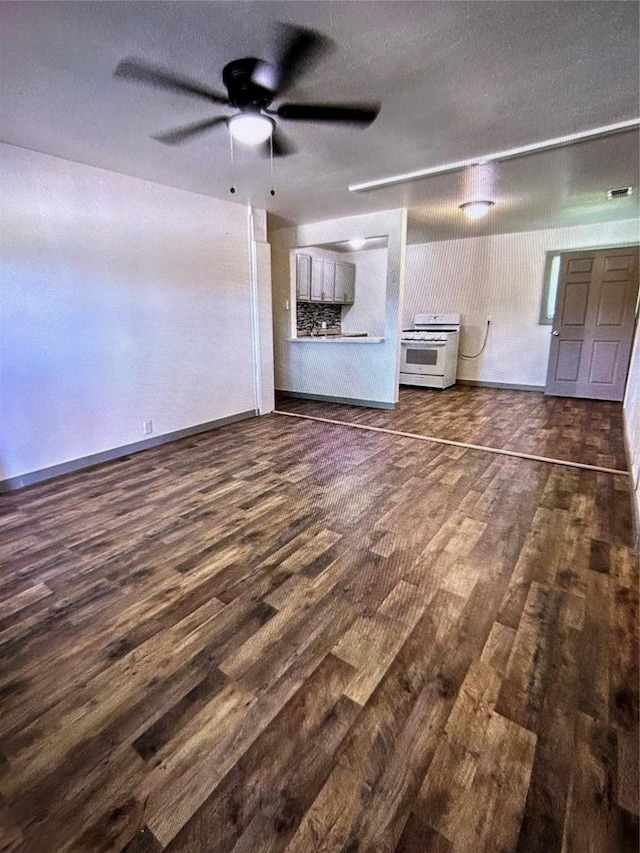 unfurnished living room featuring dark wood-type flooring and ceiling fan