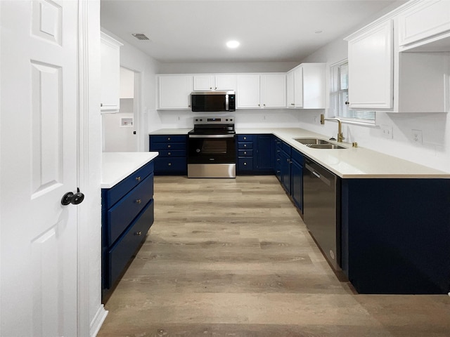 kitchen with appliances with stainless steel finishes, sink, white cabinets, and blue cabinetry