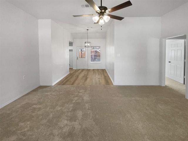 empty room with carpet flooring and ceiling fan with notable chandelier