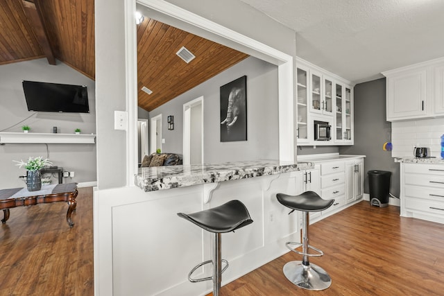 kitchen featuring dark hardwood / wood-style floors, light stone countertops, and white cabinets