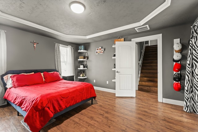 bedroom featuring dark hardwood / wood-style floors, a textured ceiling, and a tray ceiling