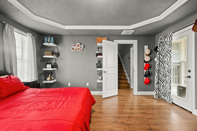 bedroom with hardwood / wood-style floors, a raised ceiling, and a textured ceiling