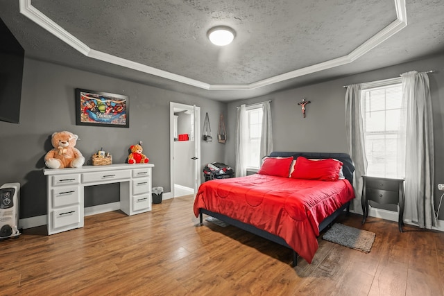 bedroom featuring dark wood-type flooring, a textured ceiling, and a tray ceiling