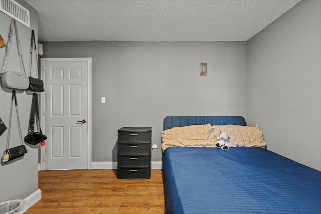 bedroom featuring hardwood / wood-style flooring and a textured ceiling