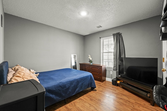 bedroom with a textured ceiling and light hardwood / wood-style flooring