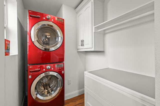 clothes washing area with cabinets, stacked washer and clothes dryer, and dark wood-type flooring