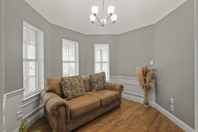 living room featuring a notable chandelier, hardwood / wood-style flooring, and a textured ceiling