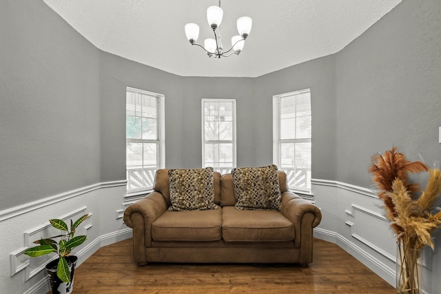 living area with an inviting chandelier, dark hardwood / wood-style floors, and a textured ceiling