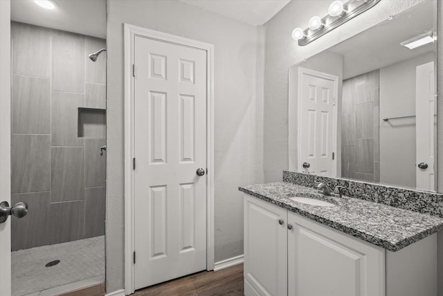 bathroom featuring hardwood / wood-style flooring, vanity, and a tile shower