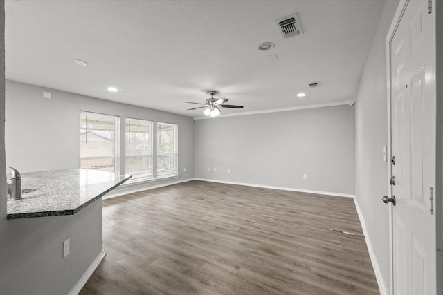 unfurnished living room featuring dark wood-type flooring, sink, and ceiling fan