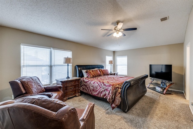 carpeted bedroom featuring ceiling fan and a textured ceiling