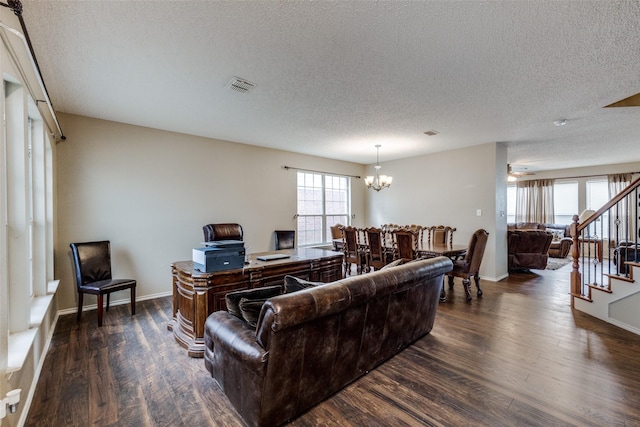 living room featuring an inviting chandelier, dark wood-type flooring, and a textured ceiling