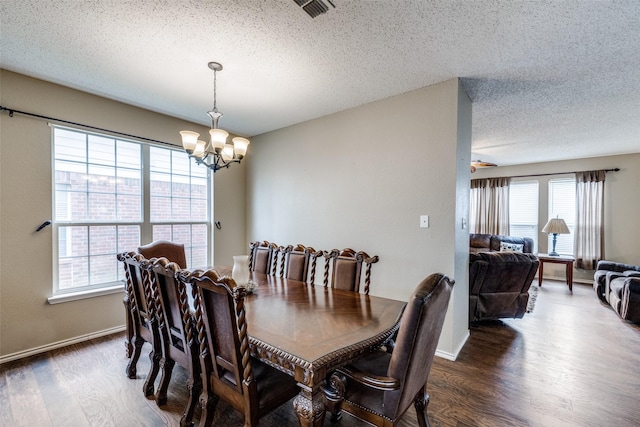 dining space featuring dark hardwood / wood-style flooring, a textured ceiling, and a chandelier