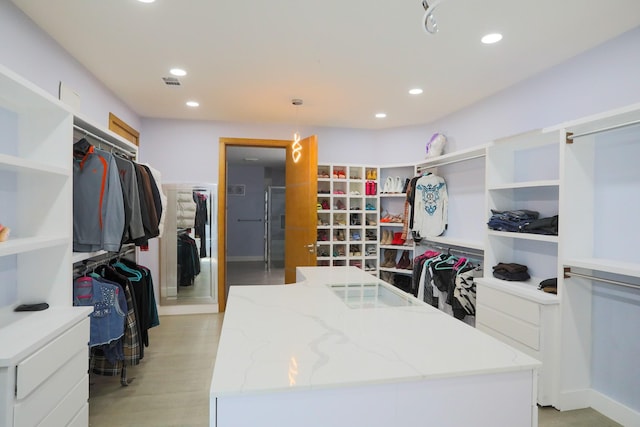 walk in closet with light hardwood / wood-style flooring