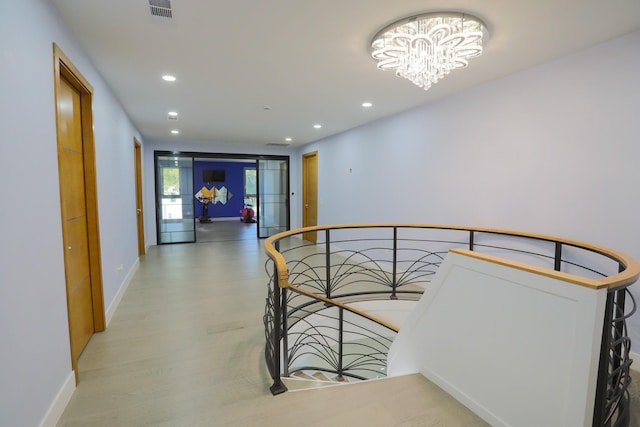 hall with hardwood / wood-style floors and a notable chandelier