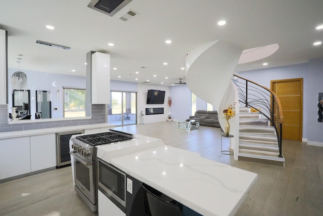 kitchen featuring built in microwave, light stone counters, light wood-type flooring, a kitchen island, and white cabinets