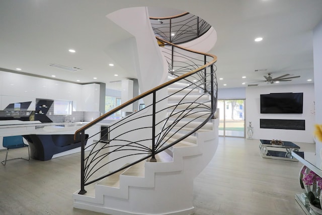 stairway featuring sink, wood-type flooring, and ceiling fan