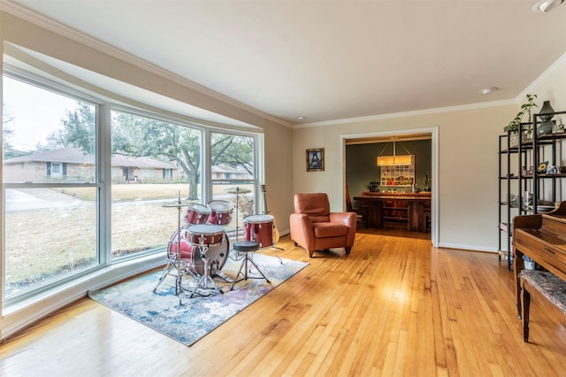 sitting room featuring crown molding, light wood-style flooring, and baseboards