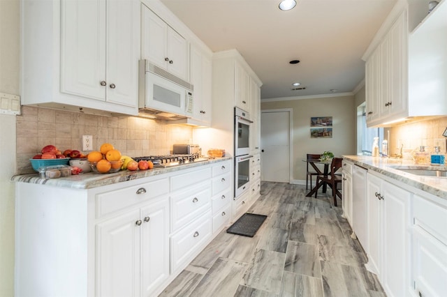 kitchen featuring light stone countertops, white cabinetry, appliances with stainless steel finishes, and a sink