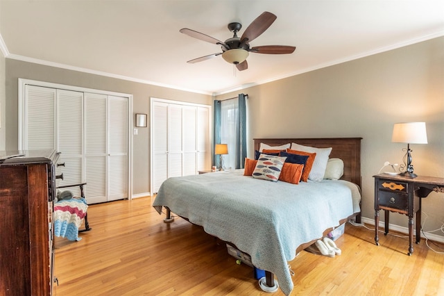 bedroom featuring light wood-type flooring, crown molding, baseboards, and two closets