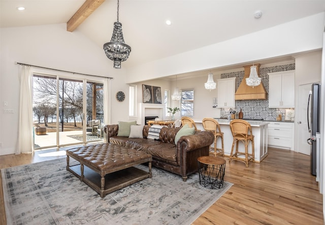 living area featuring light wood finished floors, lofted ceiling with beams, an inviting chandelier, a fireplace, and recessed lighting