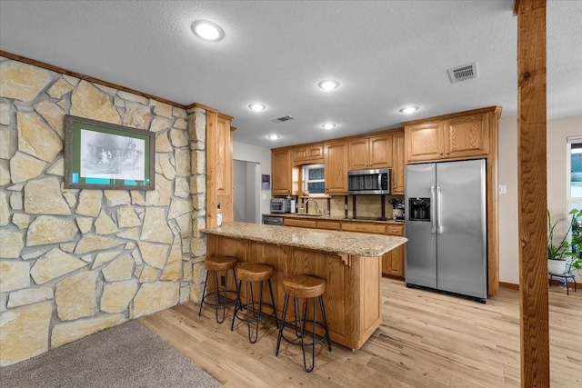 kitchen featuring appliances with stainless steel finishes, a sink, visible vents, and light wood-style floors