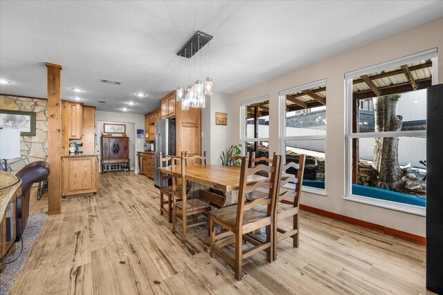 dining room featuring ornate columns and light wood-type flooring