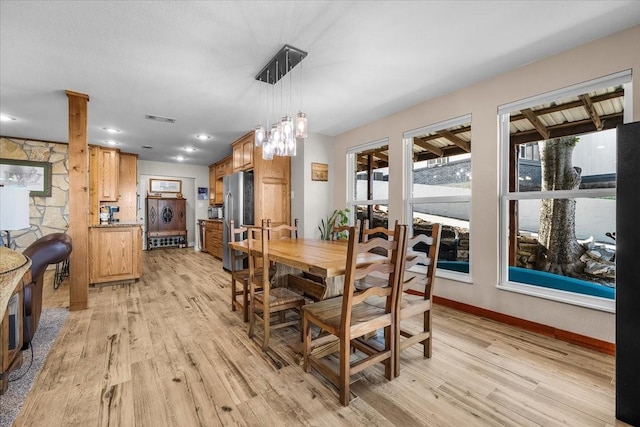 dining area with baseboards, ornate columns, visible vents, and light wood-style floors