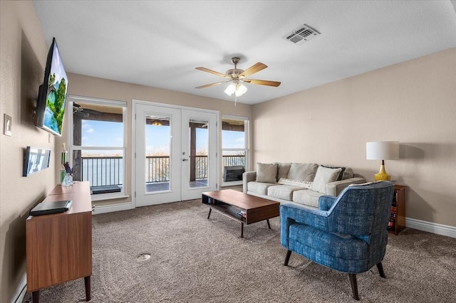 carpeted living room featuring a baseboard heating unit, ceiling fan, and french doors