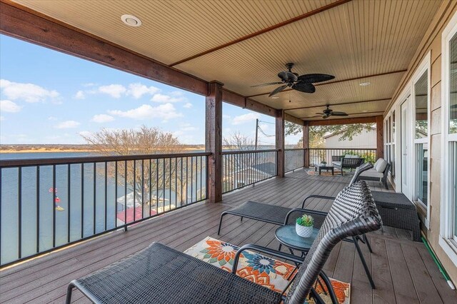 wooden deck with a water view and ceiling fan