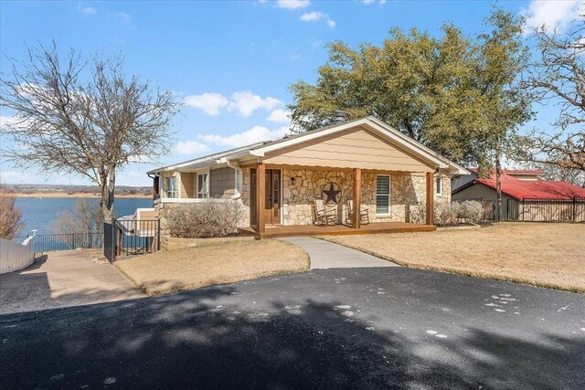 view of front of home with a water view, a porch, and a front lawn