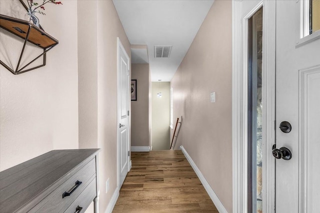 corridor with light wood finished floors, an upstairs landing, visible vents, and baseboards