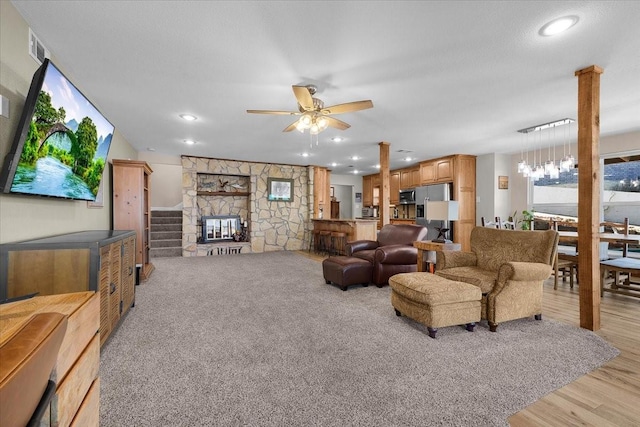 living room featuring ceiling fan, a fireplace, light hardwood / wood-style floors, and decorative columns