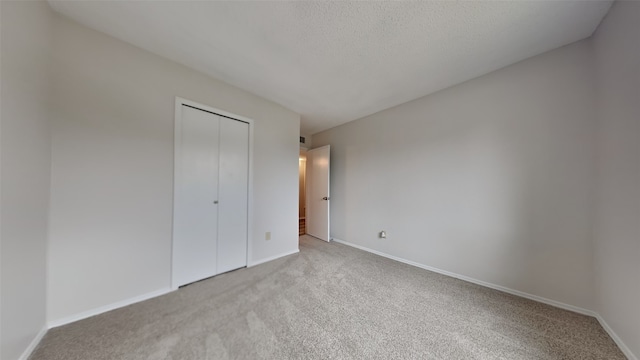 unfurnished bedroom with light carpet, a closet, and a textured ceiling