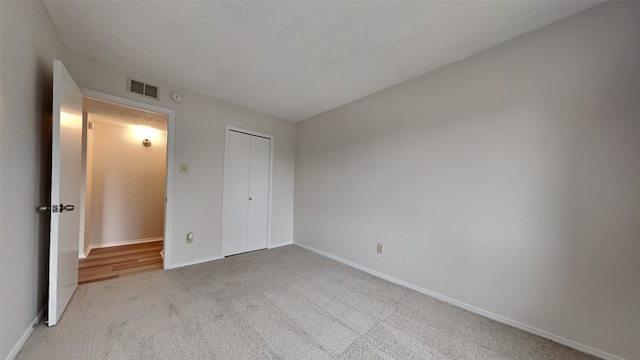 unfurnished bedroom featuring light colored carpet and a closet