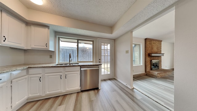 kitchen featuring light wood-type flooring, stainless steel dishwasher, sink, and white cabinets