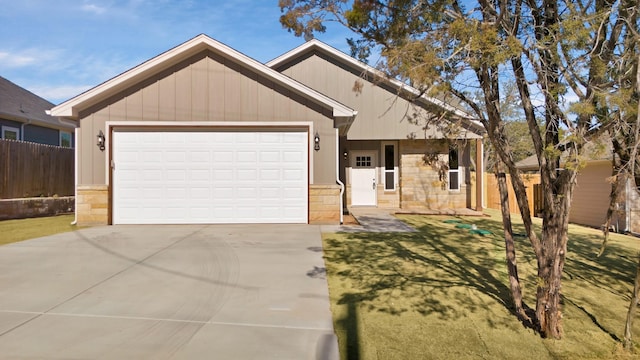 view of front of house featuring concrete driveway, fence, a garage, and stone siding