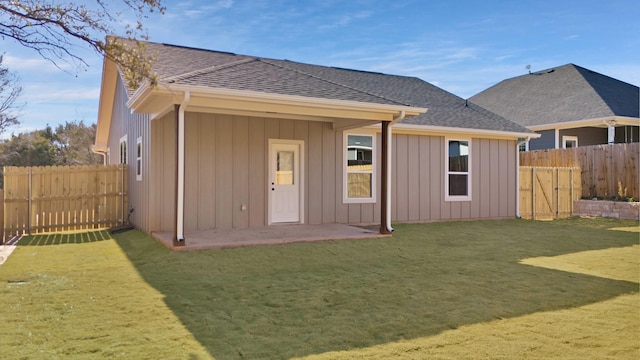 rear view of property with a fenced backyard, a patio, a yard, and roof with shingles